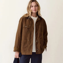 Load image into Gallery viewer, A woman stands against a plain off-white studio background wearing a brown corduroy jacket over a white top, navy wide-leg pants, and beige shoes, while holding a folded navy and red striped garment.