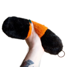 Load image into Gallery viewer, Hand holding a black and orange plush toy against a plain background