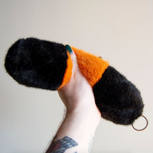 Load image into Gallery viewer, Hand holding a black and orange plush toy against a plain background