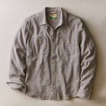 Load image into Gallery viewer, A long-sleeve button-up shirt with a fine vertical stripe pattern in gray and white, featuring two chest pockets and brass buttons, laid flat on a neutral beige background.
