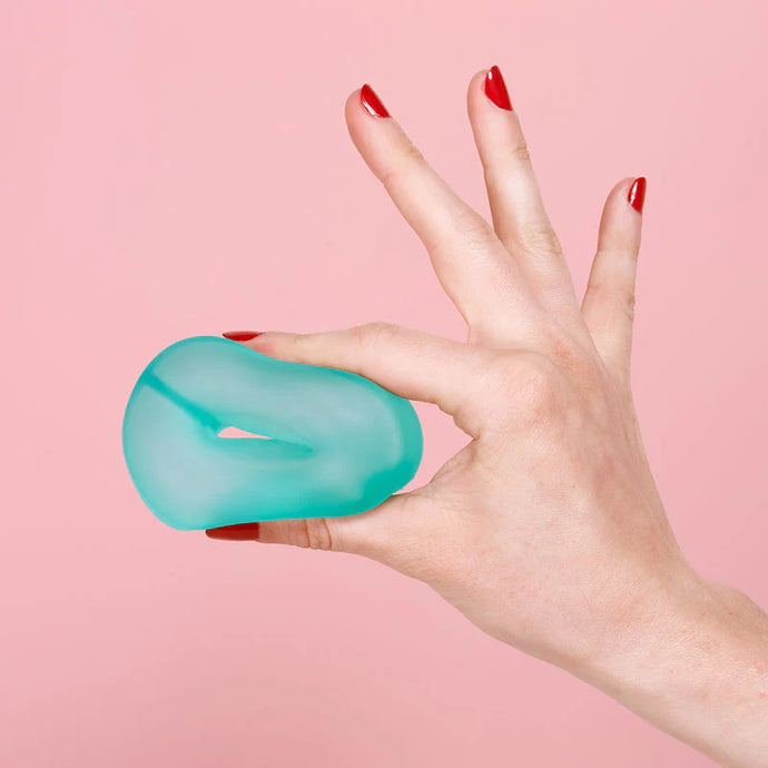 Hand holding a teal gel roller against a pink background
